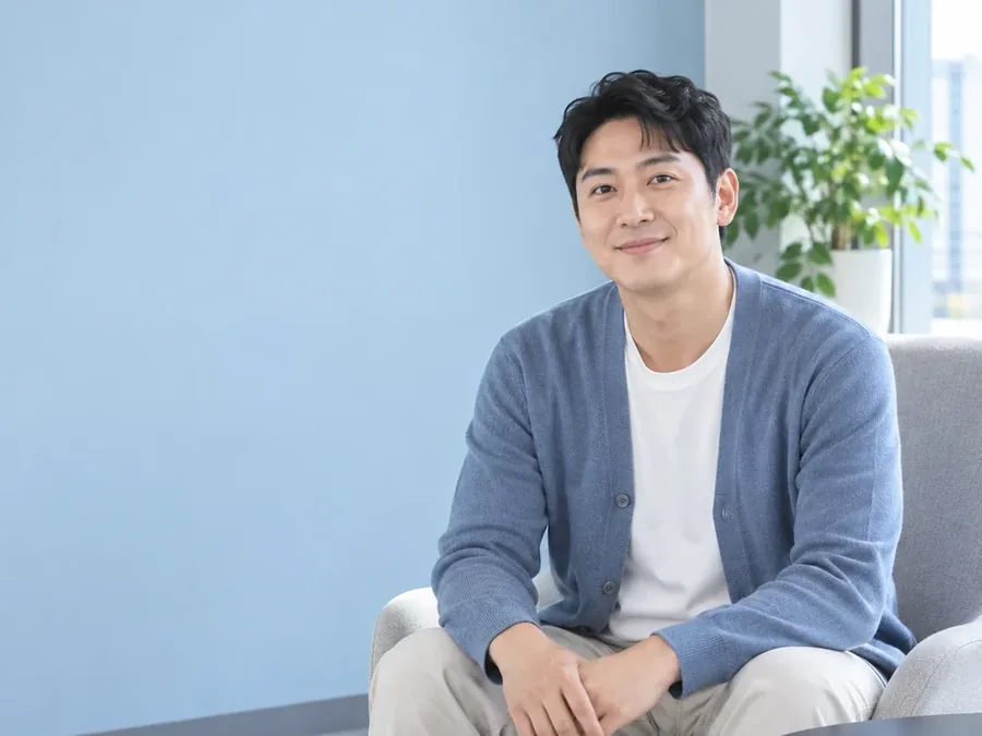 의자에 앉아 웃는 카디건 차림 남성