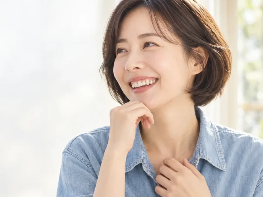 하늘색 셔츠를 입고 턱을 괸 채 환하게 웃는 여성
